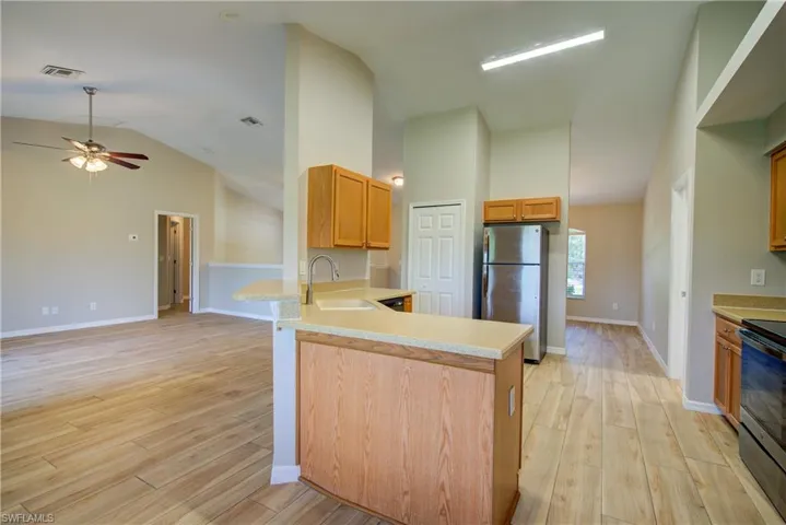 Kitchen with freestanding refrigerator, light wood-type flooring, a peninsula, electric range oven, and open floor plan