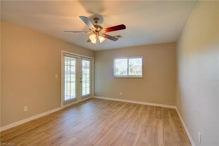Unfurnished room with light wood-style floors, ceiling fan, and french doors