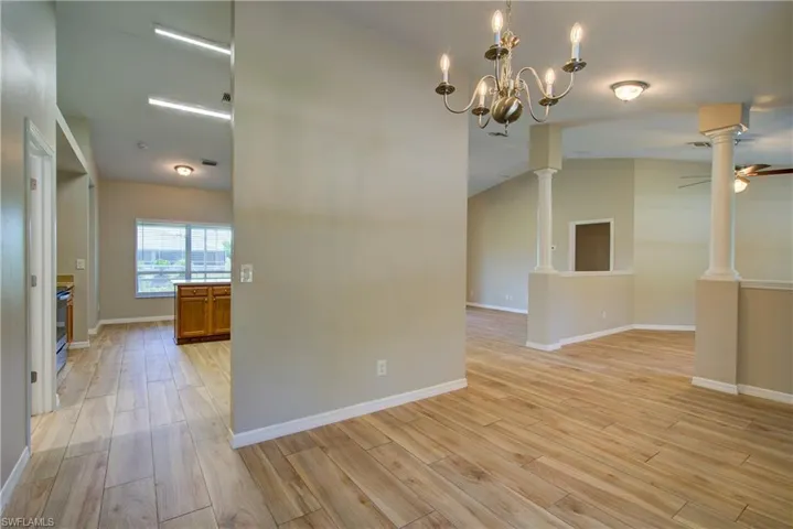 Unfurnished room featuring light wood-style floors, lofted ceiling, a chandelier, and a ceiling fan