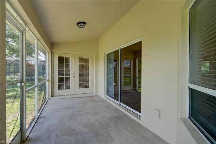 Unfurnished sunroom with tile patterned flooring and lofted ceiling