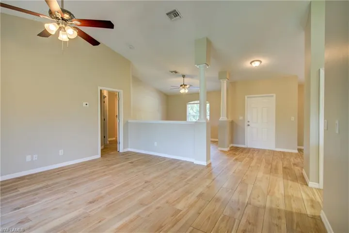 Spare room with light wood-style floors, vaulted ceiling, and ceiling fan