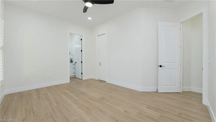 Unfurnished bedroom featuring light wood-style floors, recessed lighting, a ceiling fan, and ensuite bathroom
