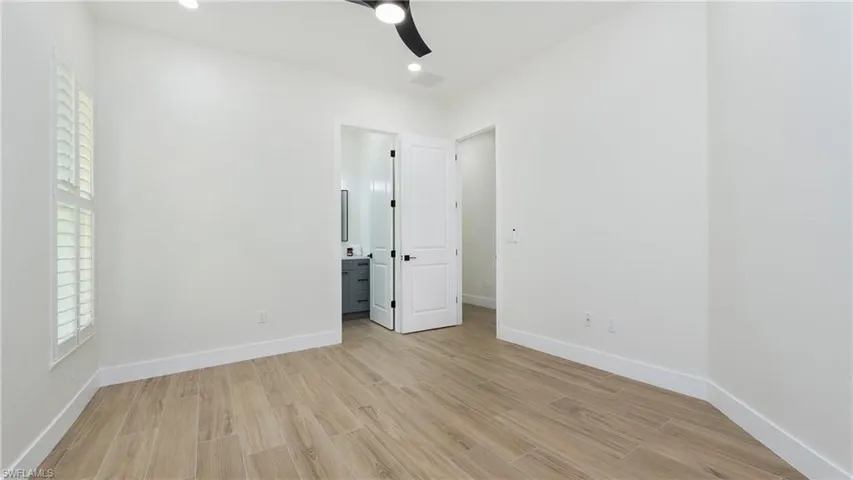 Unfurnished bedroom featuring light wood-style floors, ceiling fan, connected bathroom, and recessed lighting