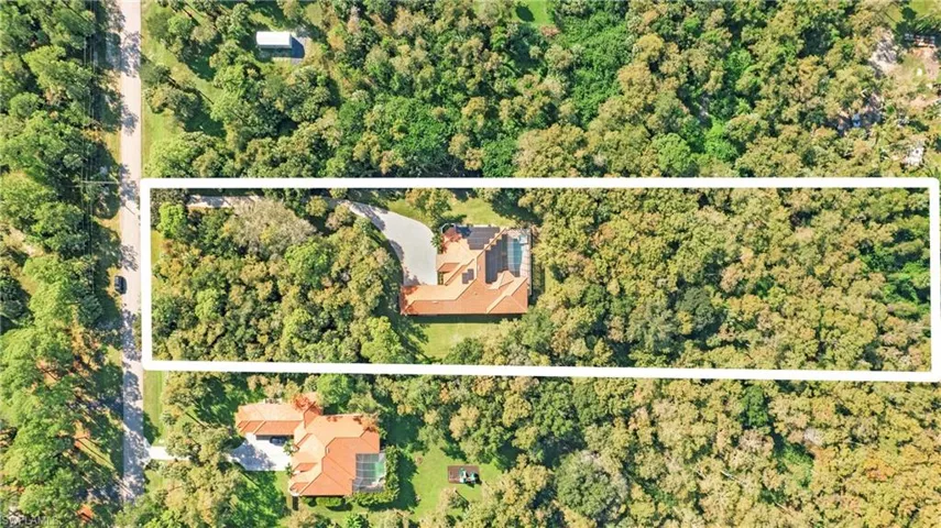 Aerial view of property and surrounding area with a forest