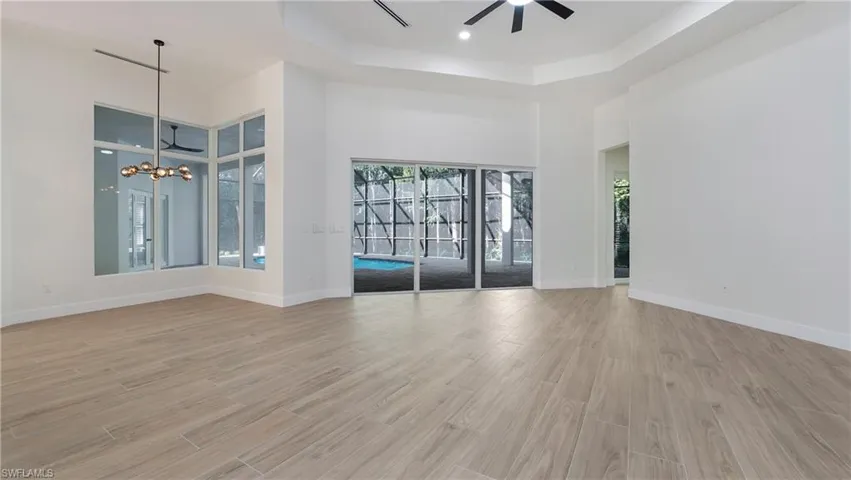Unfurnished room with a raised ceiling, light wood-style floors, a towering ceiling, recessed lighting, and ceiling fan