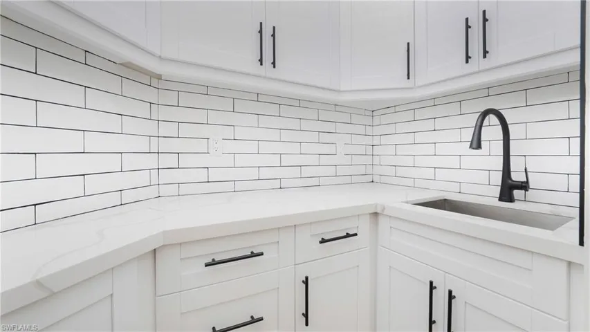 Kitchen featuring white cabinetry, light stone counters, and tasteful backsplash