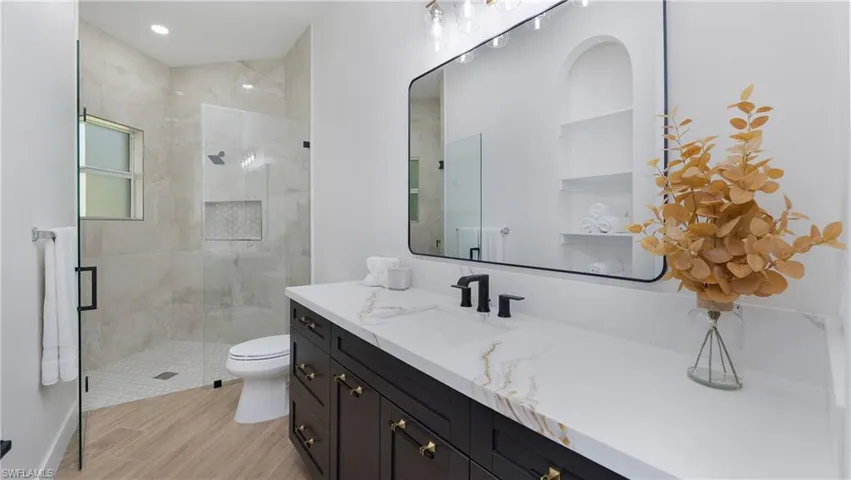 Full bath with vanity, a stall shower, and light wood finished floors