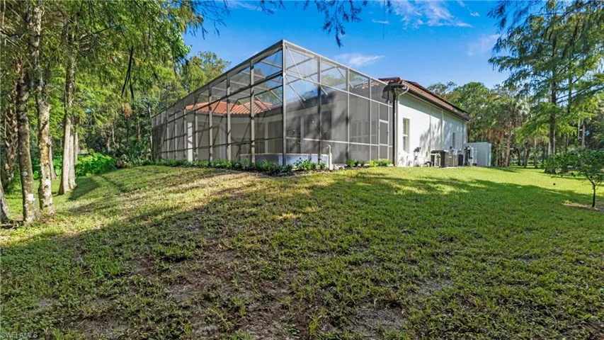 View of grassy yard featuring a sunroom and glass enclosure