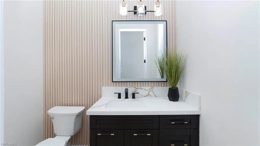 Half bathroom with vanity, a chandelier, and wallpapered walls