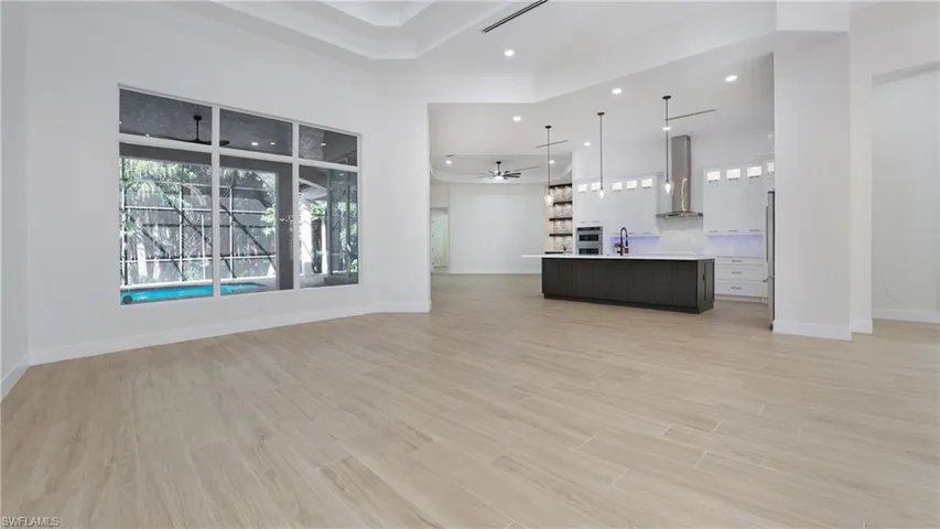 Unfurnished living room with light wood-style floors, ceiling fan, recessed lighting, and a high ceiling