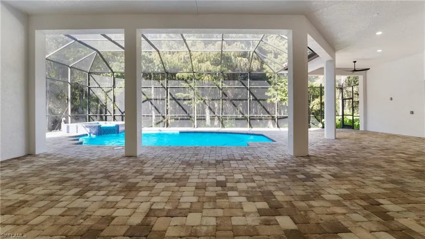 View of swimming pool with a patio, glass enclosure, a sunroom, and a pool with connected hot tub