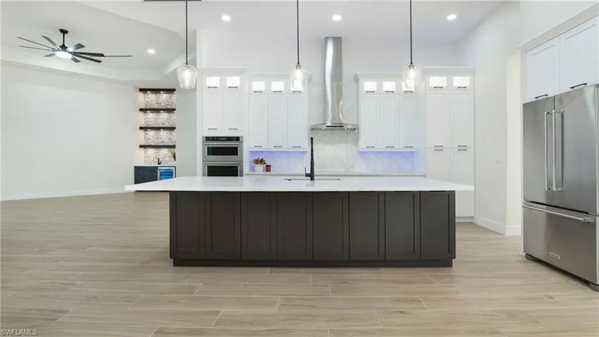 Kitchen with stainless steel appliances, glass insert cabinets, white cabinets, wood finish floors, and recessed lighting