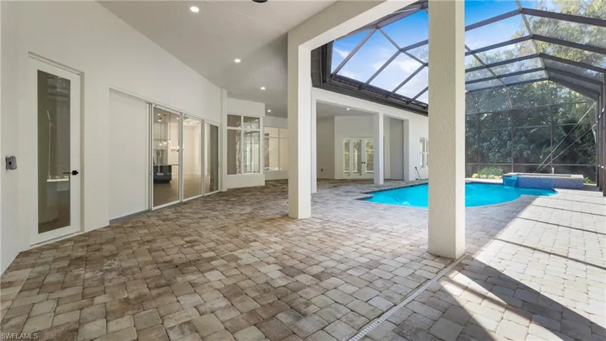 View of pool featuring a patio, a lanai, a sunroom, a pool with connected hot tub, and french doors