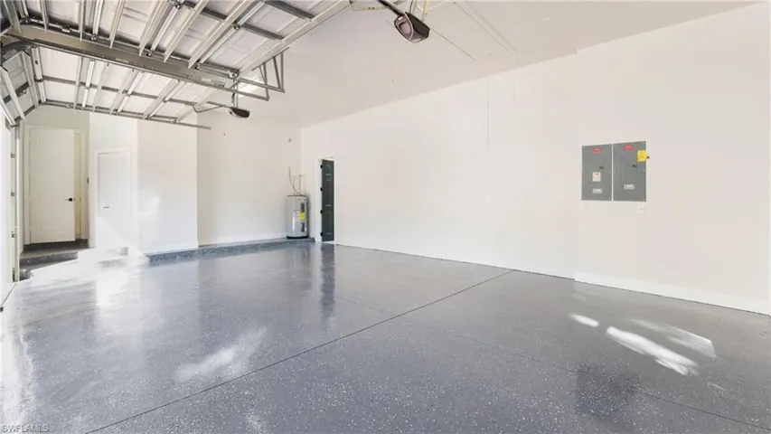 Garage with electric panel, electric water heater, and a garage door opener
