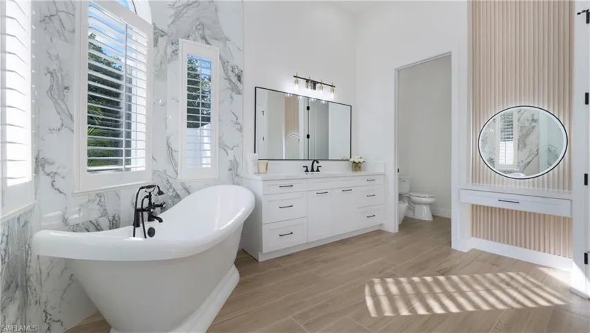 Bathroom featuring a freestanding tub, vanity, wood tiled floors, and tile walls