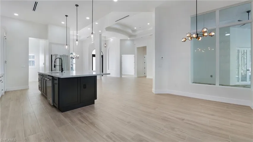 Kitchen featuring a chandelier, white cabinets, open floor plan, dark cabinets, and a towering ceiling
