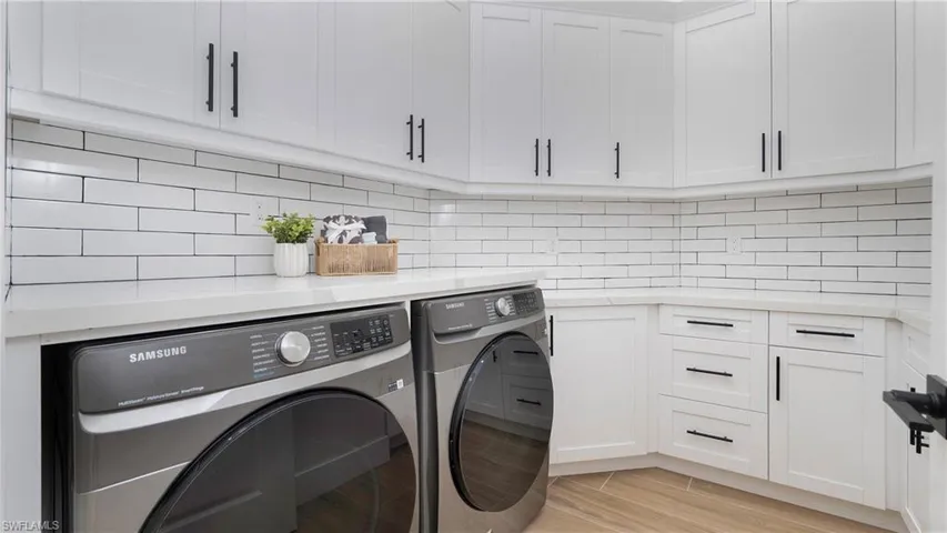 Washroom with light wood-style flooring, washer and clothes dryer, and cabinet space