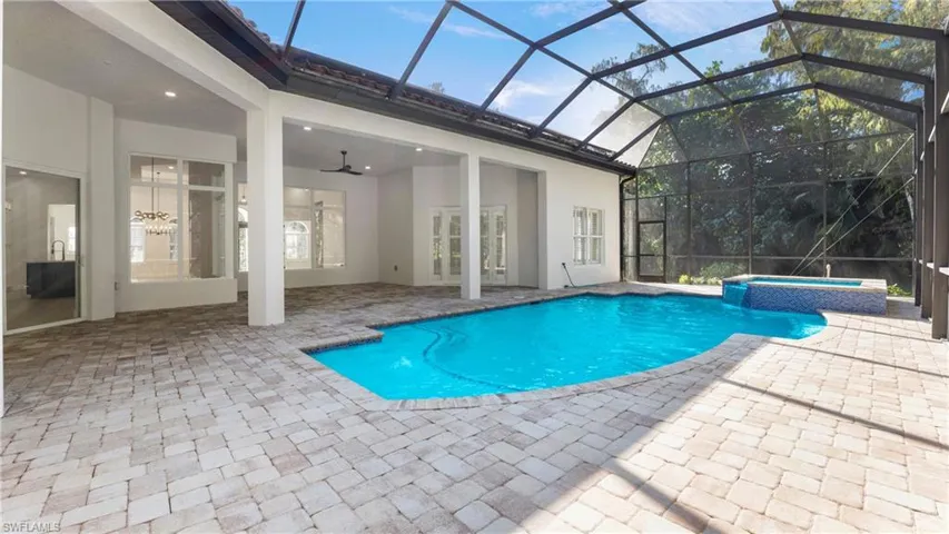 View of pool featuring glass enclosure, ceiling fan, a pool with connected hot tub, a patio area, and a sunroom