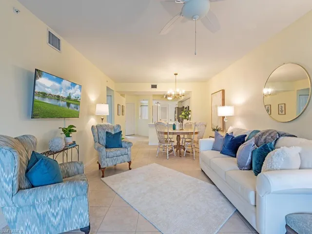 Tiled living room with ceiling fan with notable chandelier