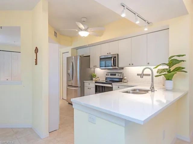 Kitchen featuring appliances with stainless steel finishes, ceiling fan, sink, tasteful backsplash, and kitchen peninsula