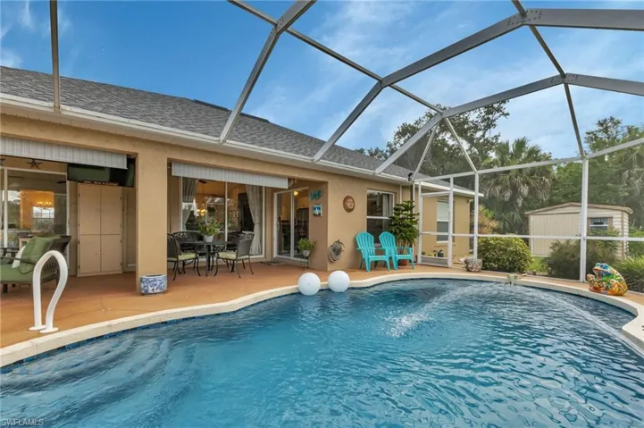 View of pool with a storage shed, a patio, and glass enclosure