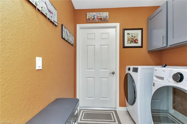 Laundry area with cabinets, light tile patterned floors, and washing machine and clothes dryer