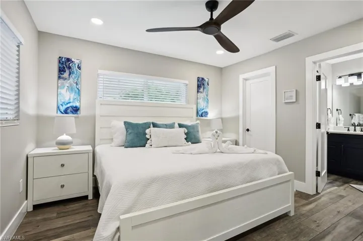 Bedroom with dark hardwood / wood-style floors, connected bathroom, sink, and ceiling fan