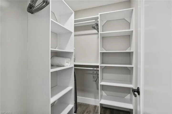 Spacious closet with dark hardwood / wood-style floors