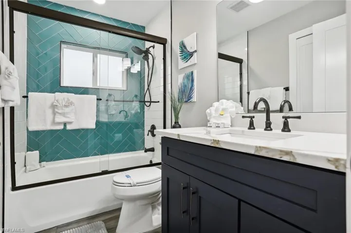 Full bathroom featuring vanity, combined bath / shower with glass door, wood-type flooring, and toilet