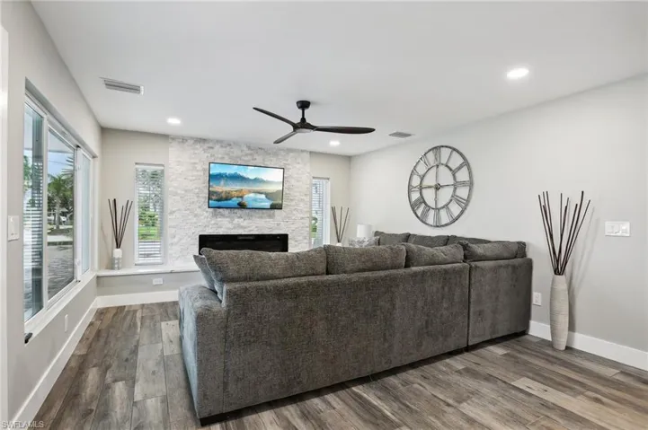 Living room featuring a fireplace, dark hardwood / wood-style flooring, and ceiling fan