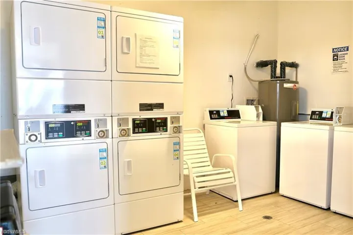 Shared laundry room with stacked washer / dryer, water heater, and washer and dryer