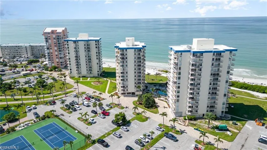 Aerial view of apartment complex and waterfront with a beach
