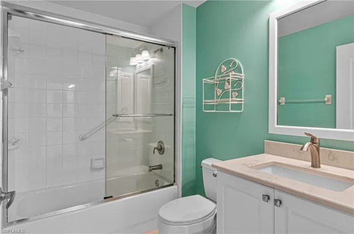 Full bathroom featuring shower / bath combination with glass door, vanity, and toilet
