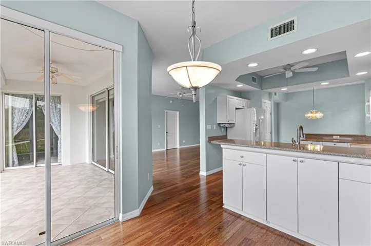 Kitchen featuring white cabinetry, white fridge with ice dispenser, hardwood / wood-style flooring, and sink