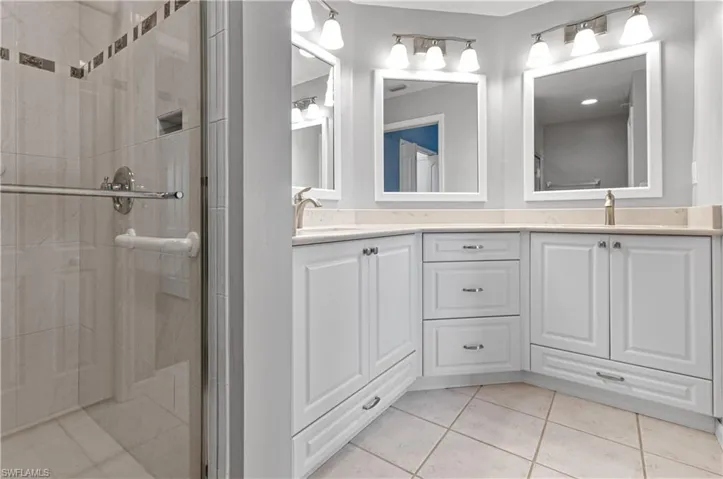 Bathroom featuring tile patterned flooring, a shower with shower door, and vanity
