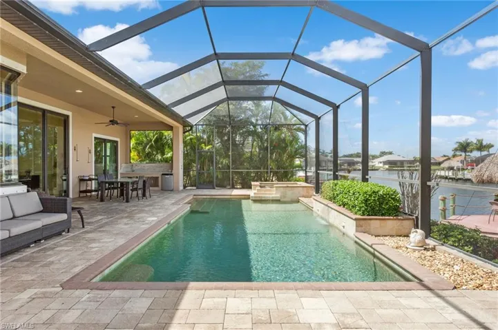 View of pool, pool cage, and lanai looking from east to west.