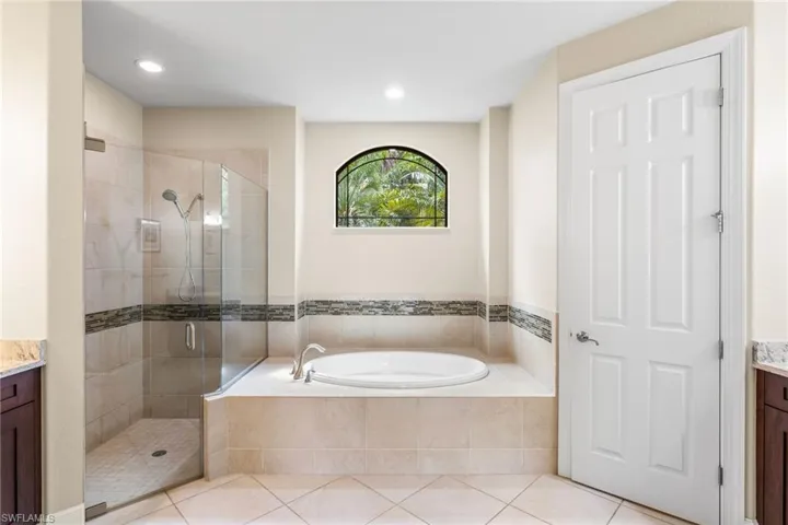 Master Bathroom with glass enclosed walk-in shower, garden tub, and door to private water closet on right.