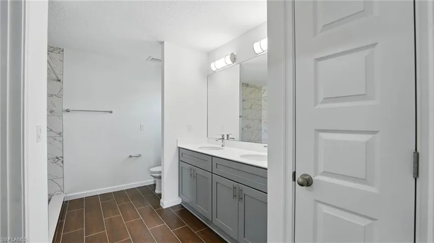 Bathroom featuring double vanity, wood tiled floors, and a textured ceiling