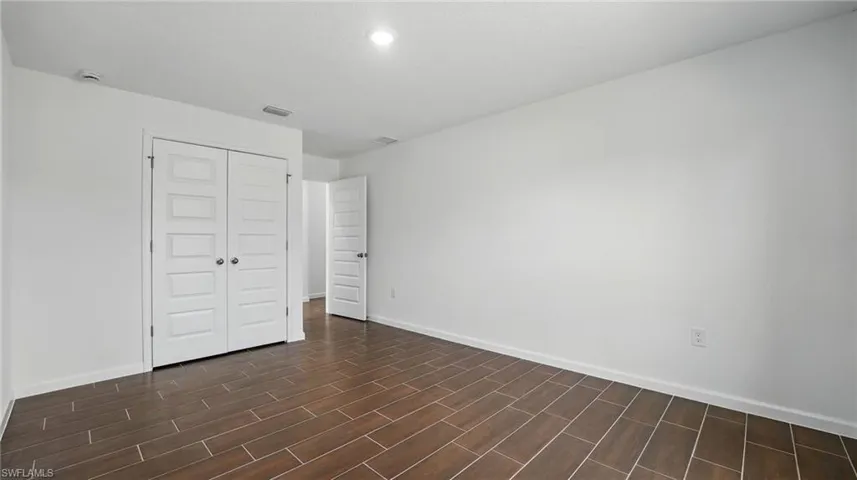 Unfurnished bedroom with a closet and wood finish floors