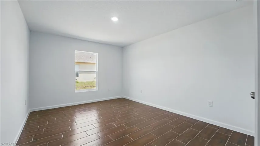 Spare room featuring baseboards and wood tiled floors