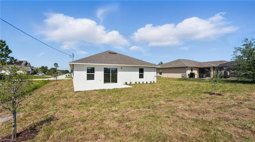 Rear view of property featuring stucco siding, a patio area, and a yard