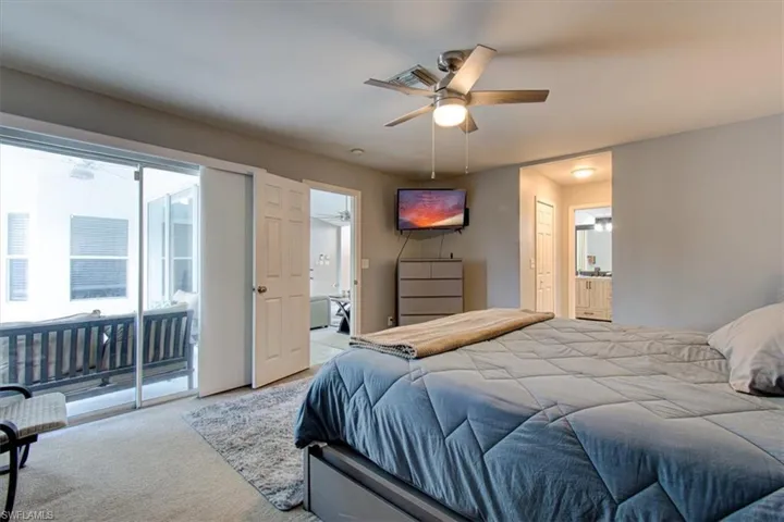 Carpeted bedroom with access to outside, ensuite bathroom, and ceiling fan