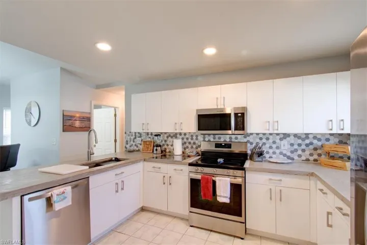 Kitchen with appliances with stainless steel finishes, tasteful backsplash, light countertops, a peninsula, and recessed lighting