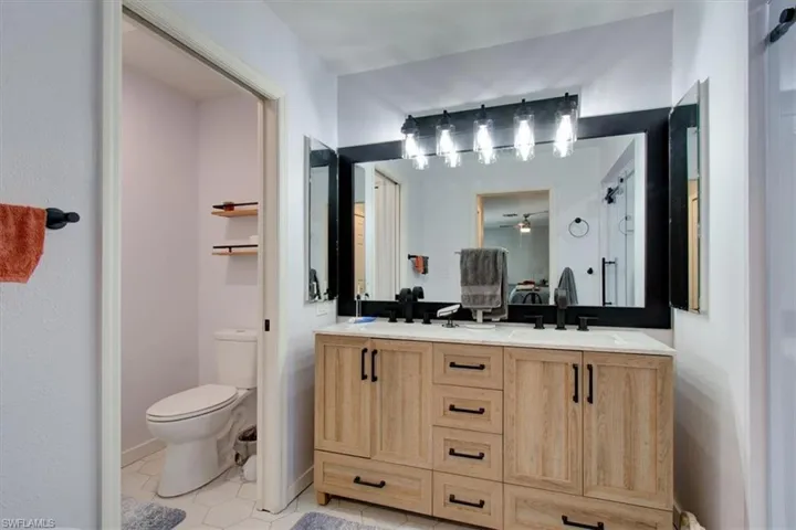 Full bathroom with double vanity, tile patterned floors, and a ceiling fan
