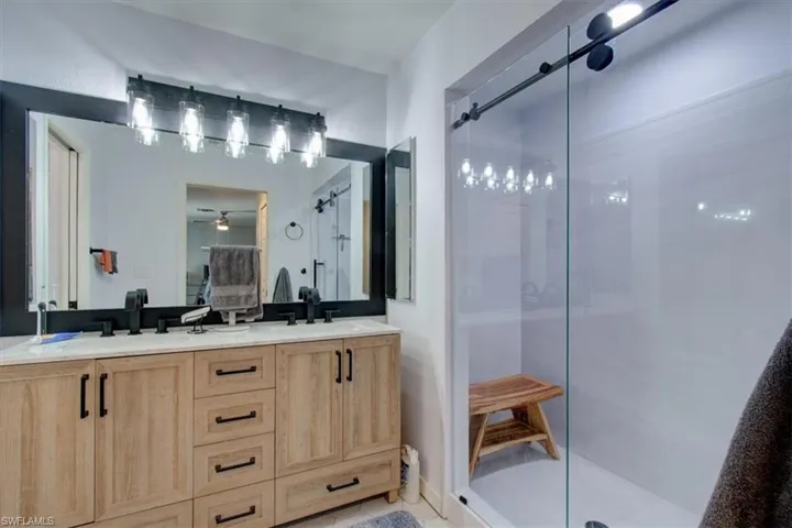 Bathroom featuring a stall shower, double vanity, a ceiling fan, and connected bathroom