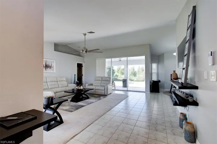 Living room with light tile patterned floors, ceiling fan, and lofted ceiling
