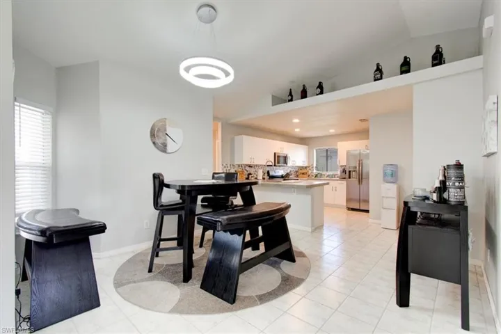 Dining space featuring light tile patterned floors and vaulted ceiling