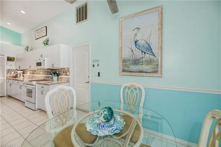 Kitchen and dining area featuring white cabinetry, granite countertops, white appliances, and a tile backsplash