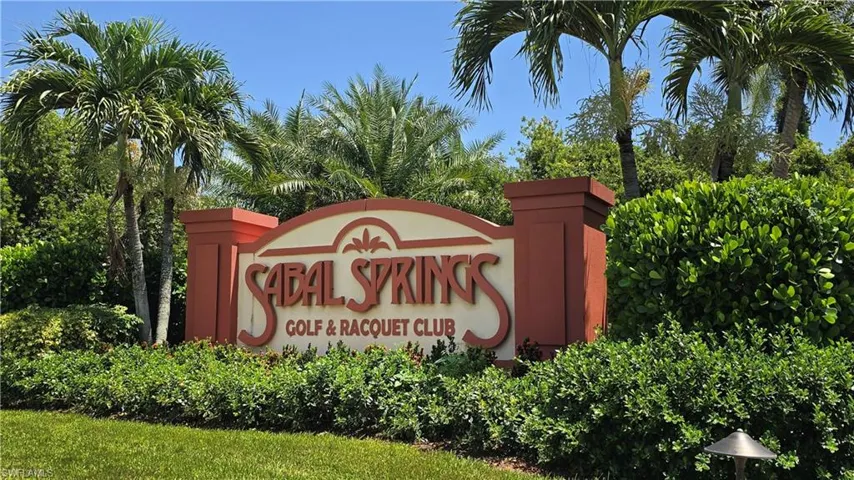 Sabal Springs Golf & Racquet Club entrance sign framed by lush tropical foliage and palm trees