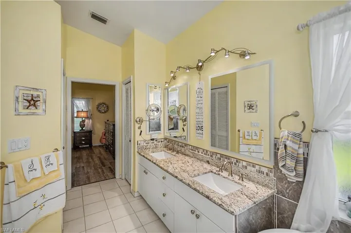 Dual vanity with integrated sinks, granite countertops, decorative tile backsplash, and individual framed mirrors